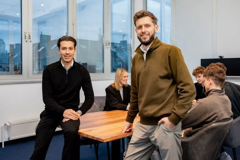 Two Rügamer & Steiner team members in front of the team at the Düsseldorf office