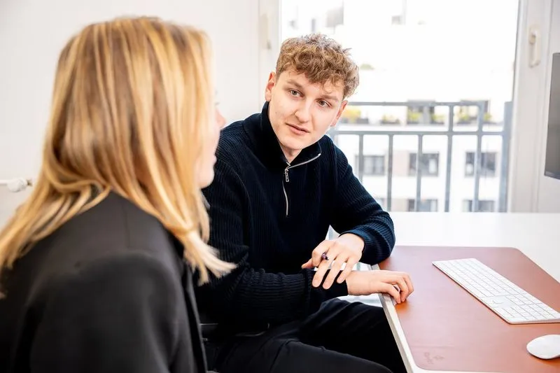 Two Rügamer & Steiner colleagues talking at a desk